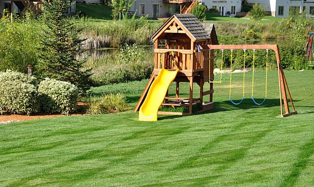 Back Yard Wooden Swing Set on Green Lawn Back Yard Wooden Swing Set on Green Lawn
